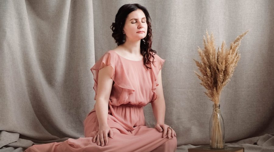 Beautiful brunette woman in a pink dress on a background of linen fabric. Copy, empty space for text.